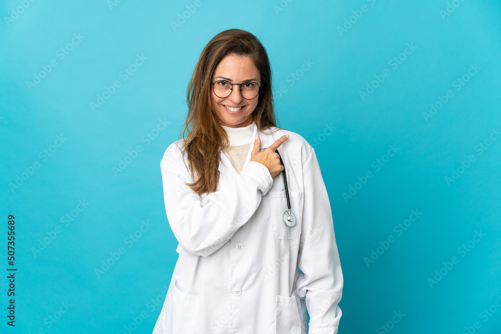 Middle age Brazilian doctor woman isolated on blue background pointing to the side to present a product Middle age Brazilian doctor woman isolated on blue background pointing to the side to present a product