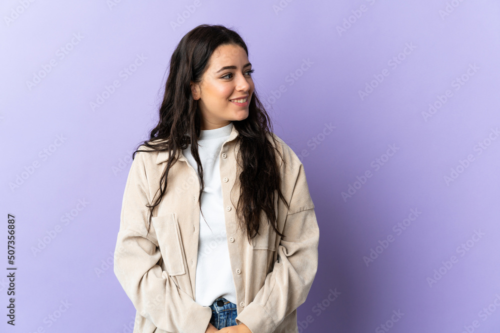 Young caucasian woman isolated on purple background looking to the side and smiling Young caucasian woman isolated on purple background looking to the side and smiling