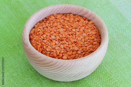 Obraz na płótnie Uncooked red lentils in wooden bowl on green background
w salonie