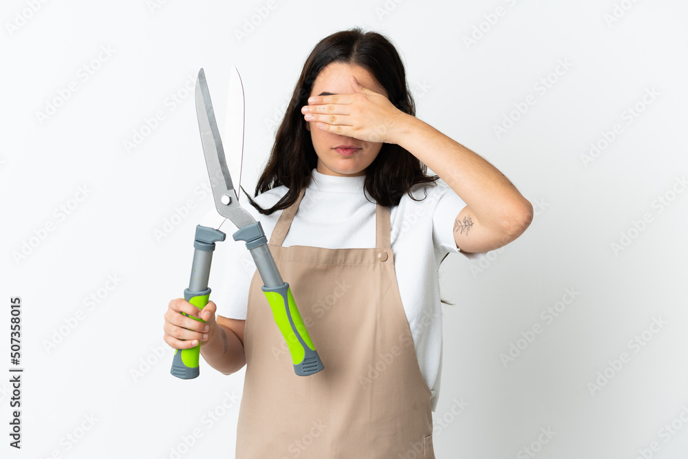 Young caucasian woman holding a plant isolated on white background covering eyes by hands. Do not want to see something Young caucasian woman holding a plant isolated on white background covering eyes by hands. Do not want to see something