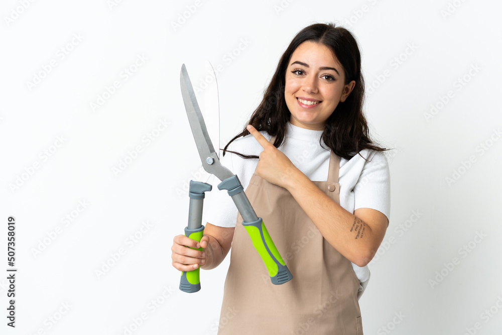 Young caucasian woman holding a plant isolated on white background pointing to the side to present a product Young caucasian woman holding a plant isolated on white background pointing to the side to present a product