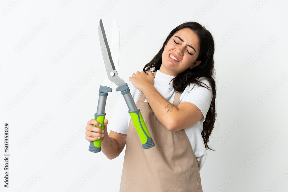Young caucasian woman holding a plant isolated on white background suffering from pain in shoulder for having made an effort Young caucasian woman holding a plant isolated on white background suffering from pain in shoulder for having made an effort