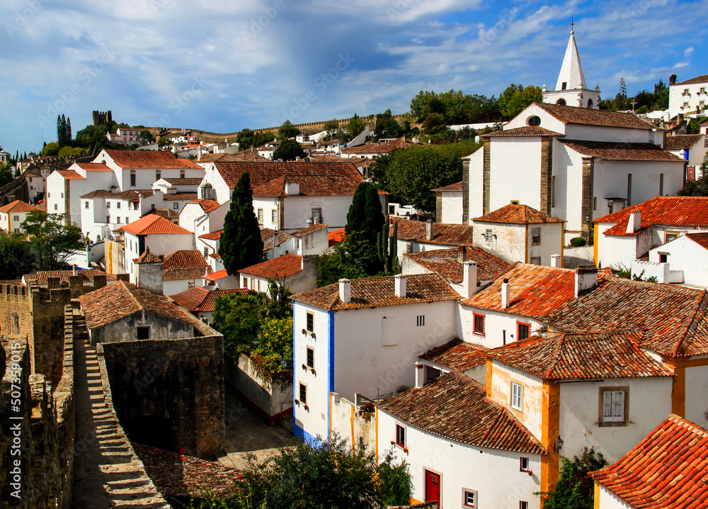 White houses, a church and a stone wall that surrounds the historic part of Obidos, near Lisbon, Portugal