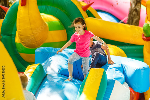 Canvas Print Happy little girl having lots of fun on a jumping castle during sliding