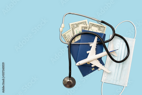 Passport, stethoscope and toy plane on blue background