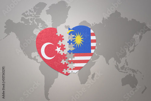 puzzle heart with the national flag of turkey and malaysia on a world map background. Concept.