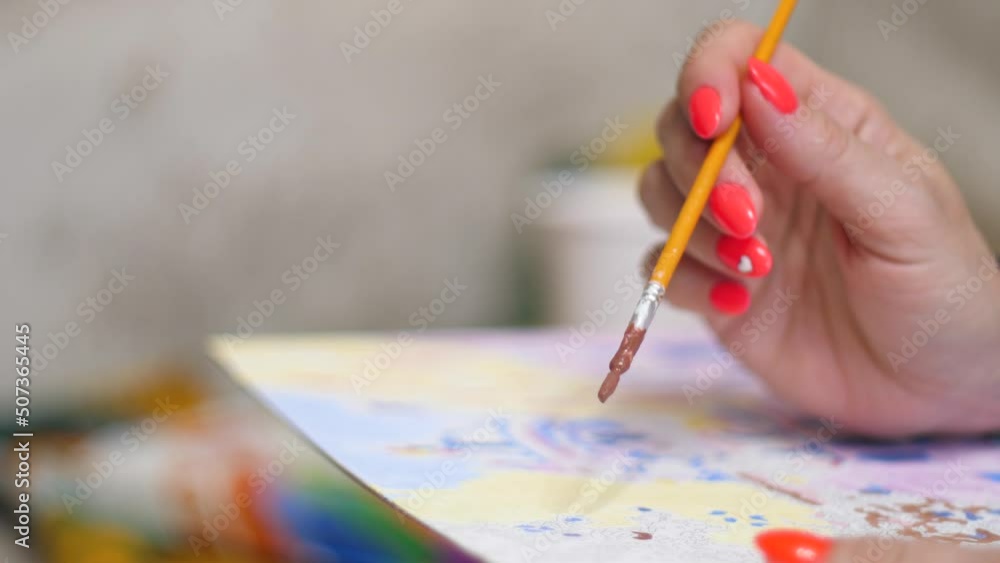 close-up female hand holding a brush and painting with watercolors .hobby housewives drawing.woman artist paints a picture.selective focus close-up female hand holding a brush and painting with watercolors .hobby housewives drawing.woman artist paints a picture.selective focus