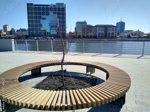 Fotografia Round wooden bench in the city park on the embankment line