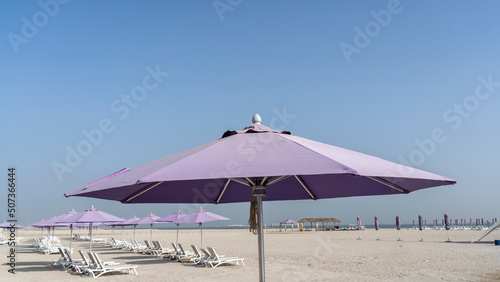 Purple beach umbrellas. Blue sky. Relaxing context. Summer holidays at the sea. General contest and location