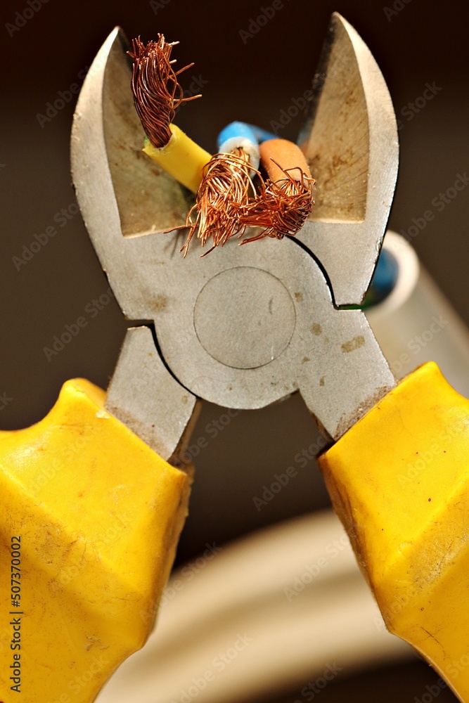 Electrical wires in the process of being cut with a side cutter. The
