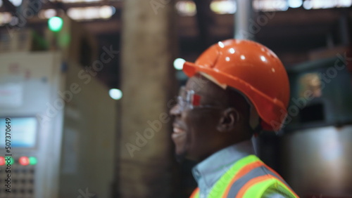 Joyful man engineer smiling at huge modern factory wearing safety uniform.