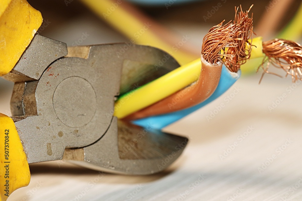 Electrical wires in the process of being cut with a side cutter. The