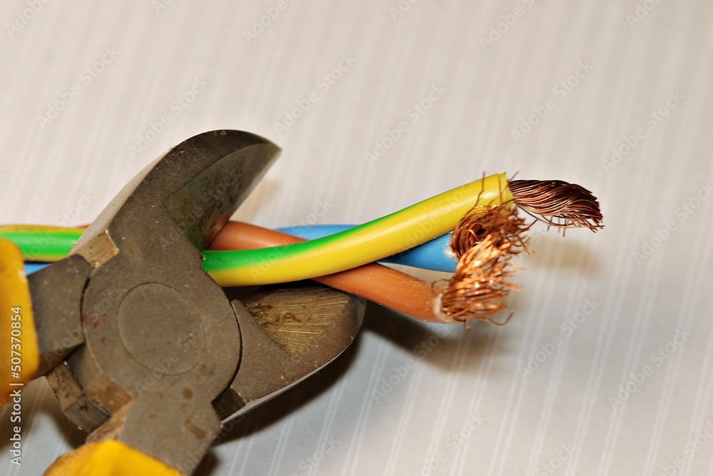 Electrical wires in the process of being cut with a side cutter. The