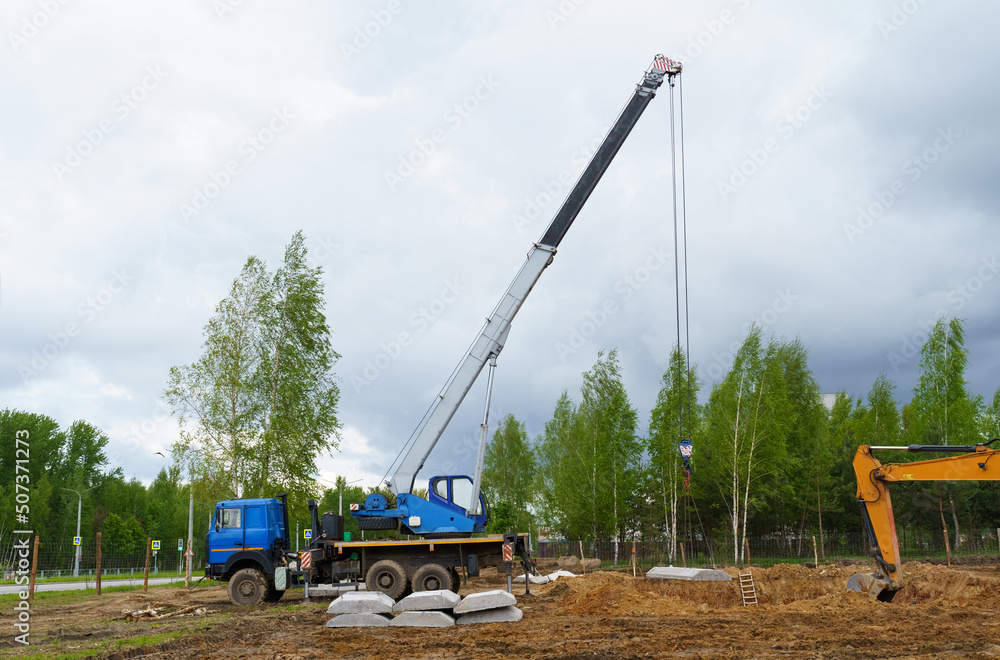 A truck crane lays slabs on the construction of a house. A truck crane lays slabs on the construction of a house.