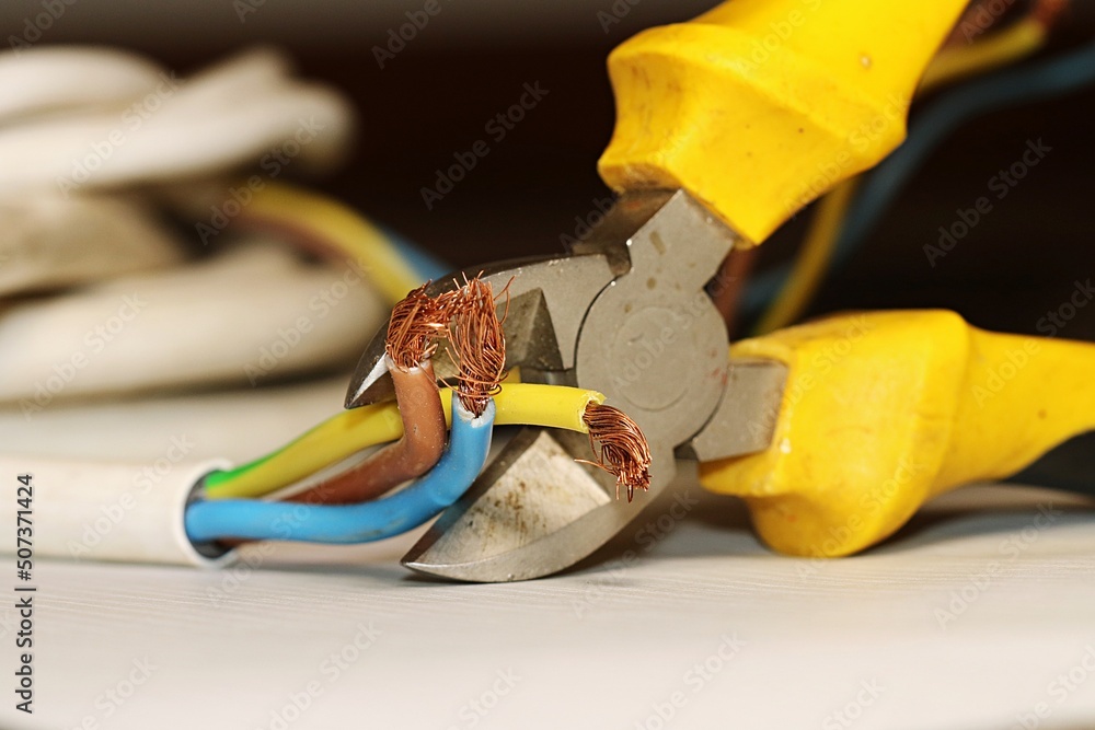 Electrical wires in the process of being cut with a side cutter. The