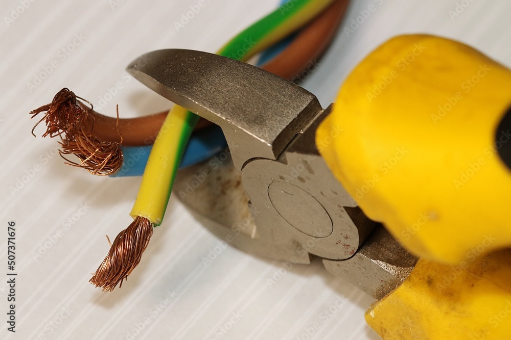 Electrical wires in the process of being cut with a side cutter. The