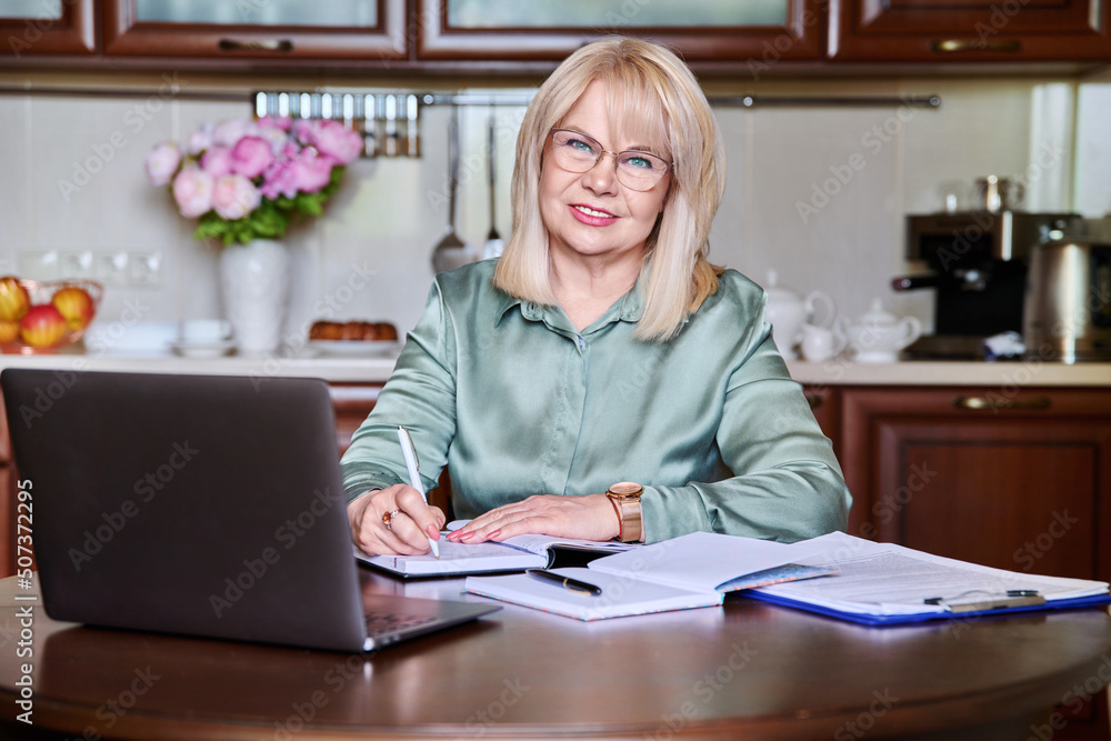 Portrait of senior business woman looking at camera working at home with laptop Portrait of senior business woman looking at camera working at home with laptop