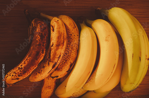Bananas of different stages of ripeness on wooden background