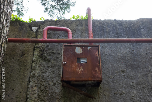 Old red pipes and gas meter on wall photo