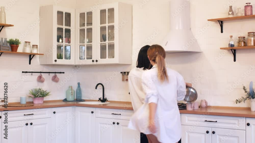 Young happy couple of lesbians have fun dancing at home in the kitchen, valentines day concept. Young happy couple of lesbians have fun dancing at home in the kitchen, valentines day concept.