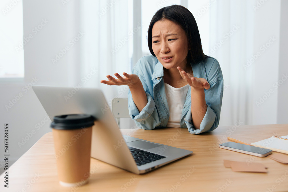 Unhappy confused young Asian cute female businesswoman hates operation problems with laptop in light office interior. Freelancer work at home. Lady corporation leader concept. Copy space Banner Offer Unhappy confused young Asian cute female businesswoman hates operation problems with laptop in light office interior. Freelancer work at home. Lady corporation leader concept. Copy space Banner Offer