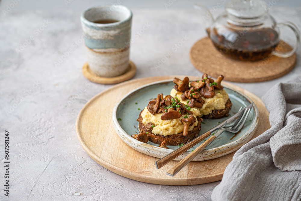 Cozy breakfast Scrambled eggs with chanterelle on buns with tea, copy space