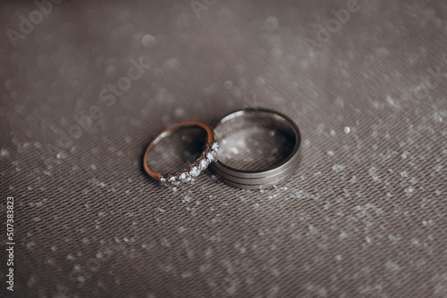 The wedding rings of the bride and groom in white gold lie on a shiny white veil. Wedding. Engagement.