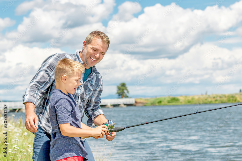 A father and son fishing together on a river bank on a beautiful summer day.