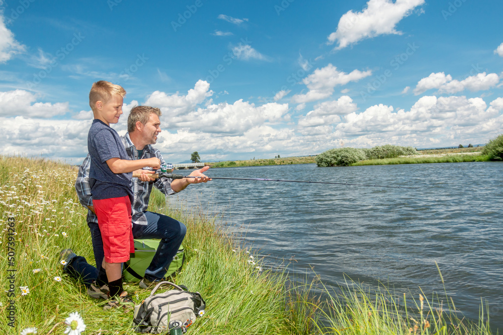 A father and son fishing together on a river bank on a beautiful summer day. A father and son fishing together on a river bank on a beautiful summer day.