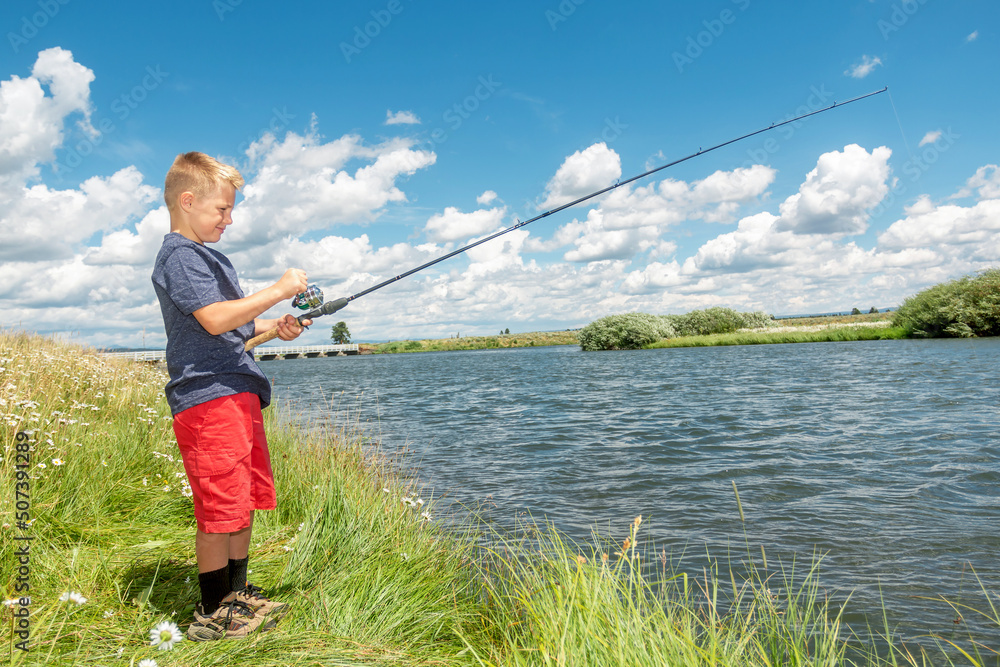 A young boy fishing on a river bank on a beautiful summer day. A young boy fishing on a river bank on a beautiful summer day.