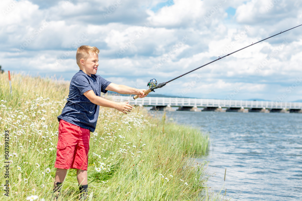 A young boy fishing on a river bank on a beautiful summer day. A young boy fishing on a river bank on a beautiful summer day.