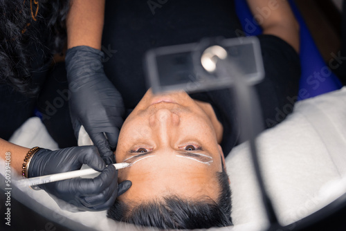 cosmetologist contouring the shape of a man's eyebrows for microblading photo