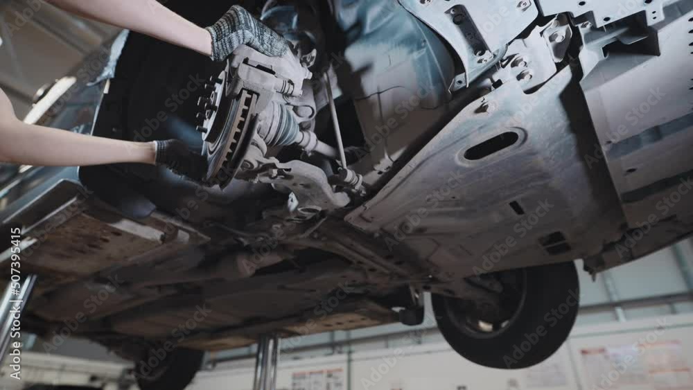 A mechanic at a service station checks the brake and steering systems. A mechanic at a service station checks the brake and steering systems.