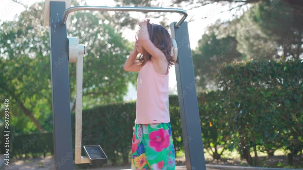 Active little girl, child, trains on simulator city park. She pulls and pushes body. Muscle strength improvement during holidays. Caucasian little girl 5 years active sport leisure outdoors. Childhood Active little girl, child, trains on simulator city park. She pulls and pushes body. Muscle strength improvement during holidays. Caucasian little girl 5 years active sport leisure outdoors. Childhood