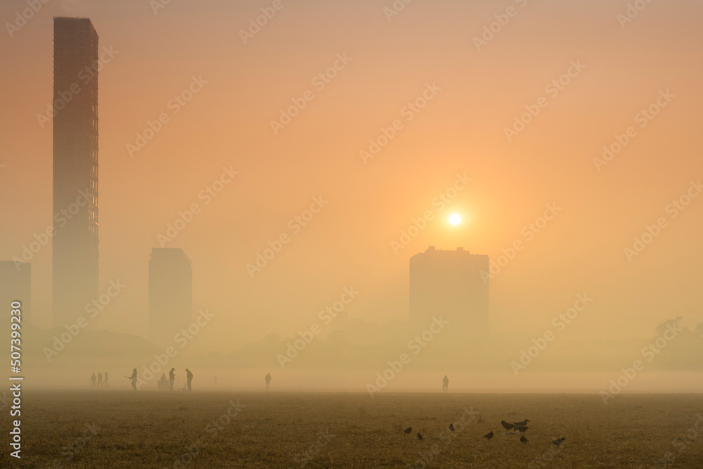 Beautiful image of sunrise at Kolkata maidan in a foggy winter morning. Sunrises at the horizon above Kolkata (formerly Calcutta) city skyscappers. Beautiful image of sunrise at Kolkata maidan in a foggy winter morning. Sunrises at the horizon above Kolkata (formerly Calcutta) city skyscappers.