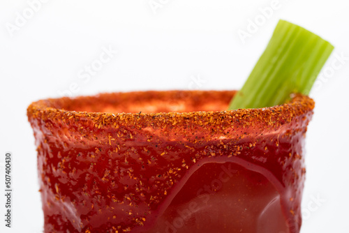 Michelada is a Mexican way of serving beer. In the image beer is mixed with tomato juice and other goodies and the glass is decorated with a frost of chamoy sauce and chili powder. photo