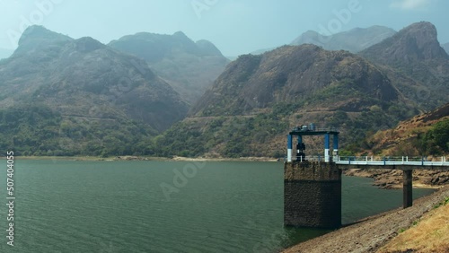 Scenic wide shot of beautiful blue waters of a reservoir seen in the foreground with majestic Anamalai Hills of the Western Ghats seen in the background shot from the corridor of a dam in 
India. photo