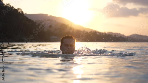 Young man swims in the sea during sunset sea view on holidays. slow motion