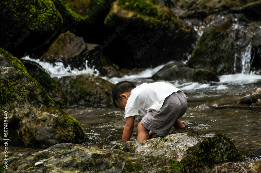 a chinese boy playing near waterfall