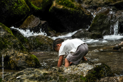 a chinese boy playing near waterfall © 曹宇