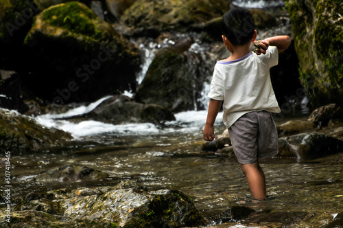 a chinese boy playing near waterfall