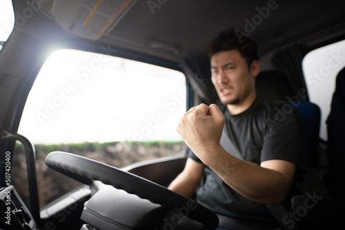 トラックの運転席で拳を握りしめる男性 © hakase420