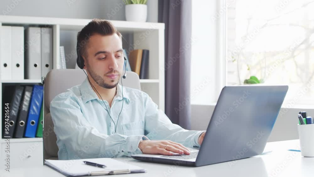 Young Man Works while Sitting in front of a Computer at Home. The Workplace of a Professional Worker, Freelancer or Student. Distance Work and Education Concept. Young Man Works while Sitting in front of a Computer at Home. The Workplace of a Professional Worker, Freelancer or Student. Distance Work and Education Concept.
