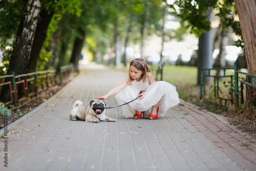European girl child in white dress in red mother's shoes with heels on walk with pug, joyful child in summer with pet European girl child in white dress in red mother's shoes with heels on walk with pug, joyful child in summer with pet