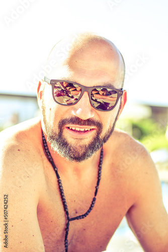 Portrait of a  happy smiling bearded Man holding   a Glass of rose Wine by the swimming pool on the empty deck of a cruise liner.Vacation and travel conceptl photo