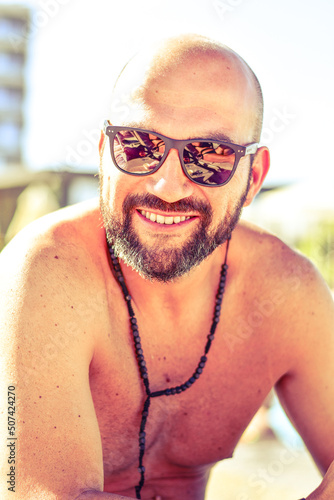 Portrait of a  happy smiling bearded Man holding   a Glass of rose Wine by the swimming pool on the empty deck of a cruise liner.Vacation and travel conceptl photo