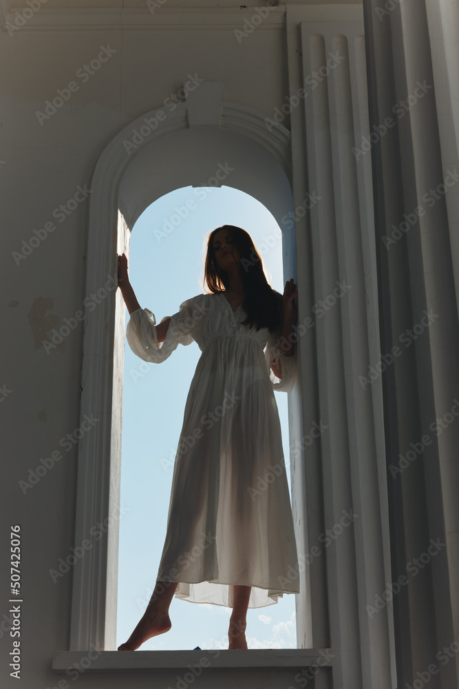 a woman in a wedding dress in an arch-shaped window opening