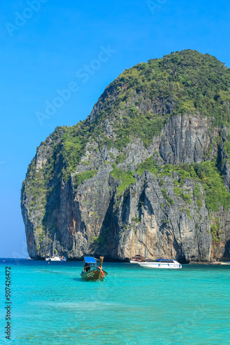 Vertical image of the longtail boat going into the beach at Maya bay at Phi Phi le, Phuket, Thailand. Background