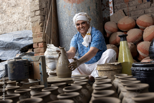 Photography Skilled hands of a potter shaping the clay into pot on spinning wheel