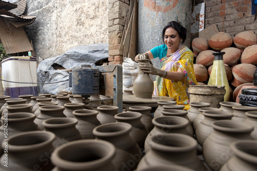 Photography Skilled hands of a female potter shaping the clay into pot on spinning wheel
